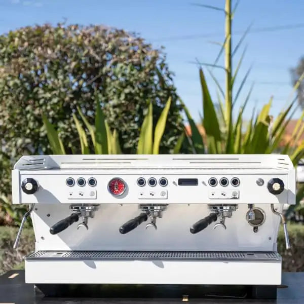Professional La Marzocco coffee machine with three group heads and multiple control knobs.