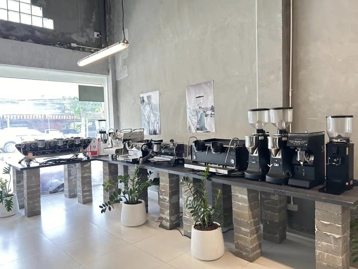 Row of commercial coffee grinders mounted on stone pedestals.